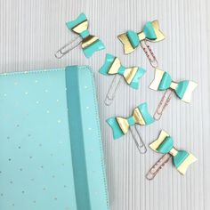 several paper clips with bows on them sitting next to a binder and clip holder