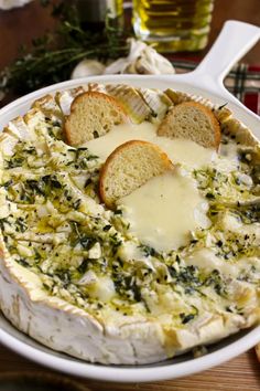 a baked cheese dish with bread and herbs on the side, ready to be eaten