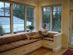 a man sitting on a couch in front of three windows