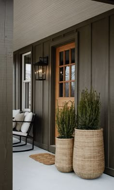 two large planters sitting on the front porch next to a chair and door way