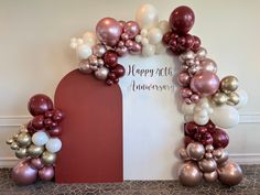 an arch made out of balloons with the words happy anniversary written on it in white and red