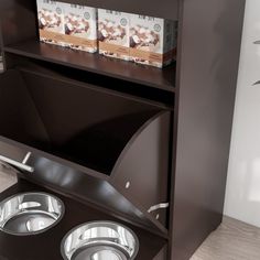 an open book shelf with two bowls on it and magazines in the bottom drawer above