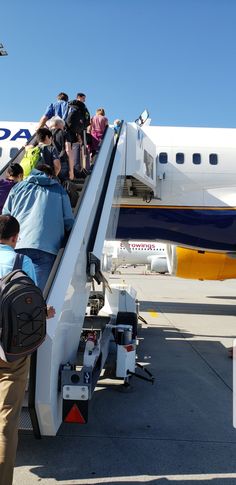 people are boarding an airplane on the tarmac with stairs leading up to their seats