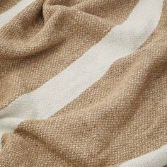 a brown and white striped blanket laying on top of a bed next to a pillow