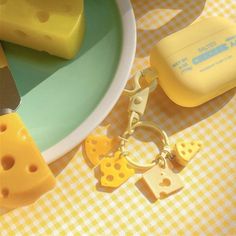 a cheese slice keychain sitting on top of a plate next to some slices of cheese