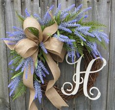 a wreath that has the letter h on it and is decorated with blue flowers, greenery and a bow