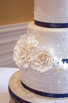 three tiered wedding cake with white flowers and blue ribbon