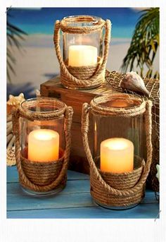 three lit candles sitting on top of a wooden table next to a basket with seashells