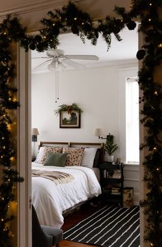 a bedroom decorated for christmas with garland and lights on the ceiling, along with a bed