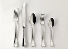 an assortment of silverware including forks, knives and spoons on a white surface