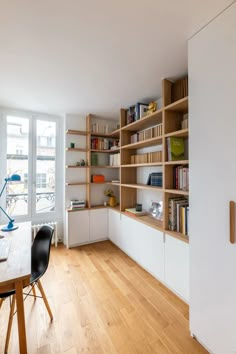 a room with wooden flooring and shelves filled with books on the wall next to a table