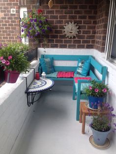 a blue bench sitting on top of a porch next to potted plants