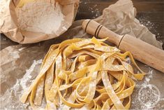 some pasta is sitting on the table next to a rolling pin