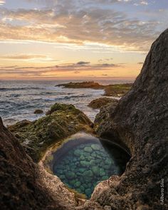 the water is blue and green as it sits in between two large rocks on the shore