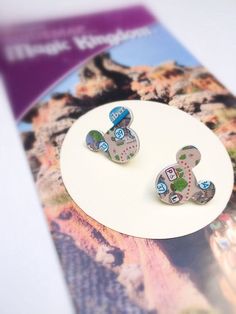 two earrings with numbers on them sitting on top of a white plate next to a brochure