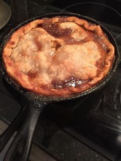 an apple pie sitting in a cast iron skillet on top of a stovetop