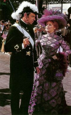 a man and woman dressed in period clothing standing next to each other on the street