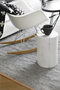 a white rocking chair sitting on top of a wooden floor next to a coffee table