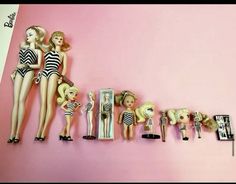 there are many dolls lined up on the wall next to each other and one is wearing a bathing suit