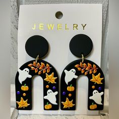 the earrings are decorated with white ghost and pumpkins on black acrylic letters