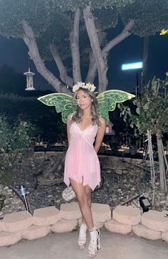 a woman dressed as a fairy standing in front of a tree