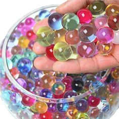 a hand holding a bowl filled with lots of colorful beads