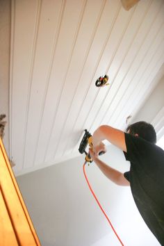 a man using a power drill to paint the ceiling