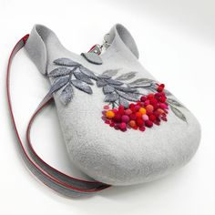 a gray purse with red, yellow and orange flowers on it's shoulder strap