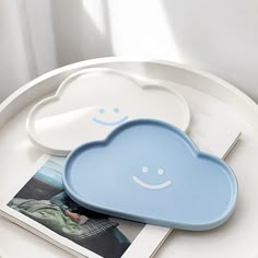 two plates with clouds on them sitting on top of a table next to a magazine