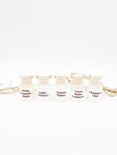 five small jars with rope around them sitting on a white surface, each containing an individual's name