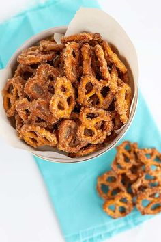 a bowl full of pretzels sitting on top of a blue napkin next to two small ones