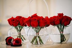 four vases with roses in them sitting on a counter top next to each other