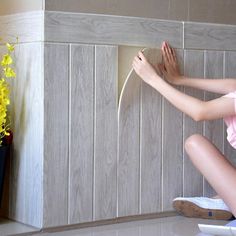 a woman is sitting on the floor with her legs crossed and she is holding a hair dryer in front of her face