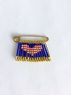 an american flag pin is shown on a white surface with blue beads and gold trim