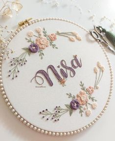 the embroidered name msm is surrounded by flowers and pearls on a white surface with scissors