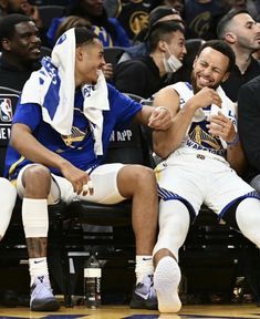 two basketball players are sitting on the bench with their arms around each other and laughing