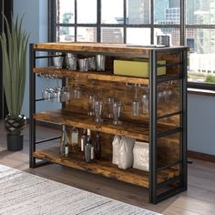 an industrial style bar cart with wine glasses and drinks on it in front of a window