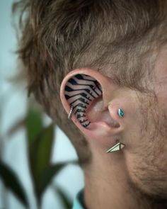 a man with ear piercings has a zebra print design on his left side behind the ear