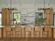 a large kitchen with wooden cabinets and marble counter tops, along with bar stools