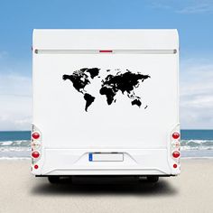 a white truck with a black world map decal on it's side parked at the beach