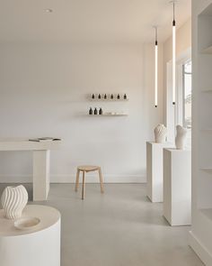 a white room with shelves and vases on the wall next to eachother