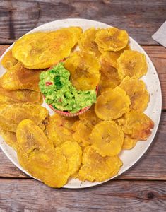 a white plate topped with potato chips and guacamole