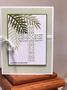 a card with a cross and palm leaves on it, sitting on top of a wooden stand