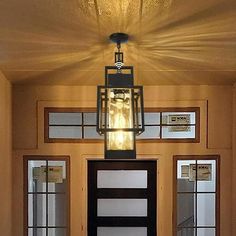 a light hanging from the ceiling in front of a door with glass panels on it