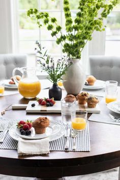 a table set for breakfast with muffins, orange juice and fresh strawberries