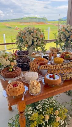 a wooden table topped with lots of different types of cakes and pies on top of it