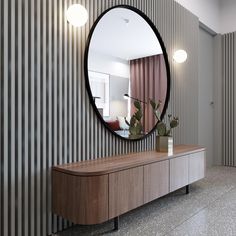 a large round mirror hanging on the side of a wall next to a wooden cabinet