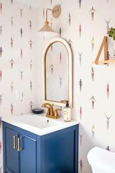 a bathroom with a sink, mirror and wallpapered walls in the shape of people