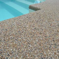 a close up view of a swimming pool with rocks and gravel on the ground next to it