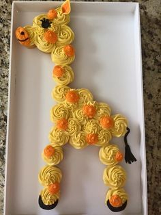 a cake in the shape of a giraffe with yellow frosting and orange flowers